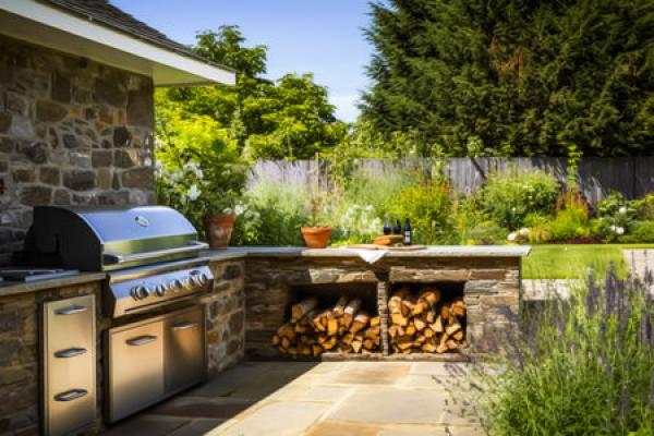 An outdoor kitchen with a grill and firewood
